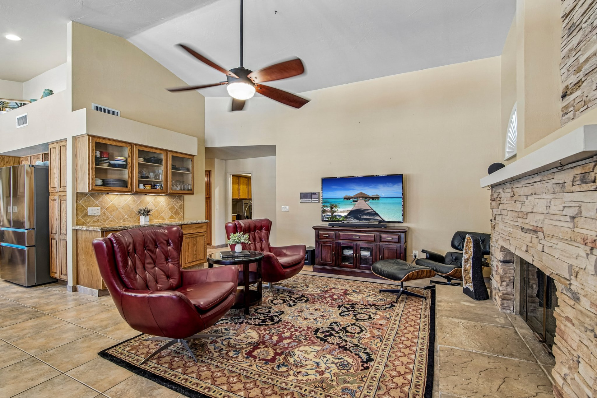 Living room with vaulted ceilings, stone fireplace, and all-tile flooring